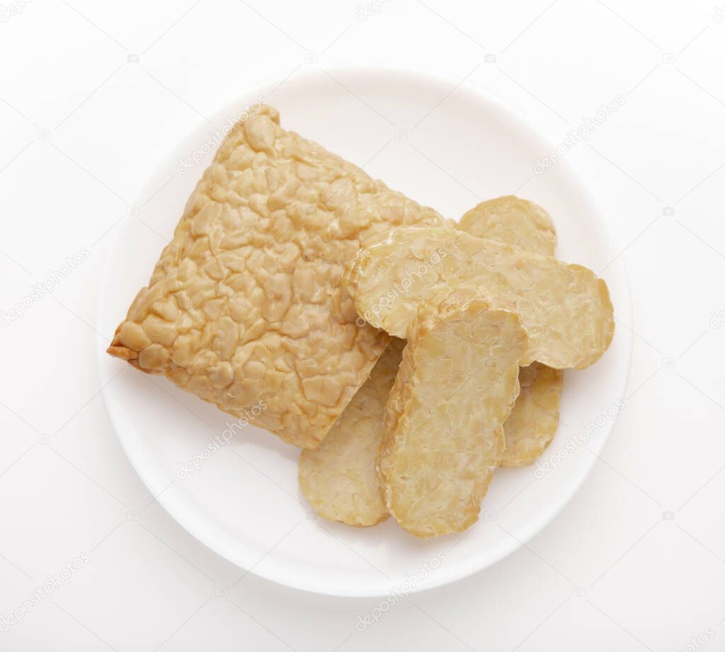Slice of cut Tempeh on white plate, top view
