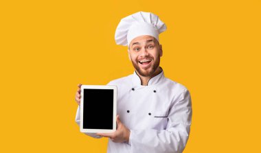 Mutlu Aşçı Sarı Stüdyo Arkaplanında Dijital Tablet Ekranı Gösteriyor