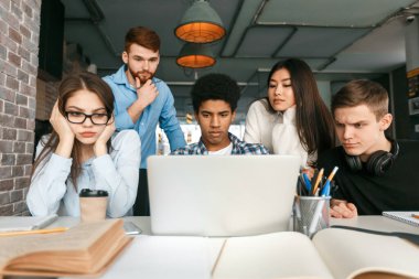 Ciddi grup arkadaşları dizüstü bilgisayarın önünde proje üzerinde çalışıyorlar