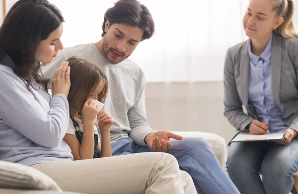 Cuidar a los padres reconfortar a su pequeña hija llorando en la oficina de psicólogos infantiles —  Fotos de Stock