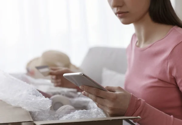 Woman unpacking online order and using cellphone