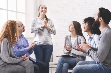 Toplum üyeleri kadınlara alkış tutuyor, terapi grubu toplantısında onu destekliyor.