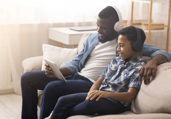Afro πατέρας και γιος βλέποντας ταινία σε ψηφιακή ταμπλέτα στο σπίτι — Φωτογραφία Αρχείου