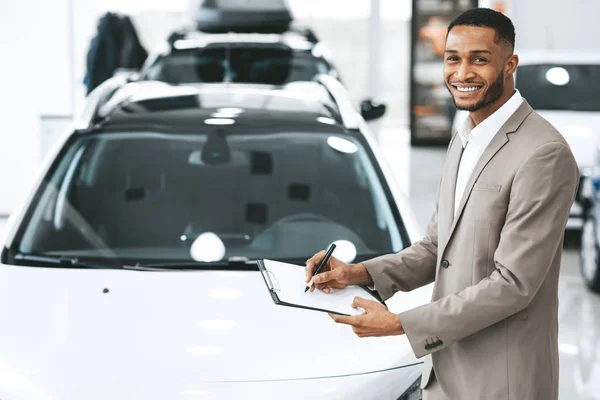 Vendedor afro-americano vendendo carro de pé no centro de concessionárias — Fotografia de Stock