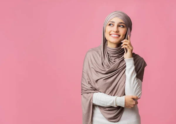 Mulher milenar em hijab falando no celular, sorrindo e olhando para longe — Fotografia de Stock