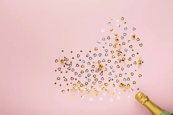 Bouteille de champagne avec coeurs confettis dorés sur rose — Photo