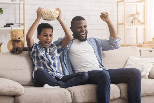 Emocionado padre negro e hijo viendo deportes en la televisión y animando — Foto de Stock