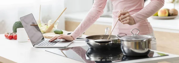 Vrouw koken lunch volgens recept op laptop — Stockfoto