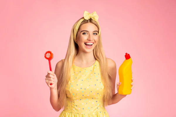 Szőke lány gazdaság ecset és narancssárga palack mosószerrel — Stock Fotó