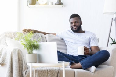 Rahat Afrikalı adam dizüstü bilgisayardan sabah haberlerinin keyfini çıkarıyor.