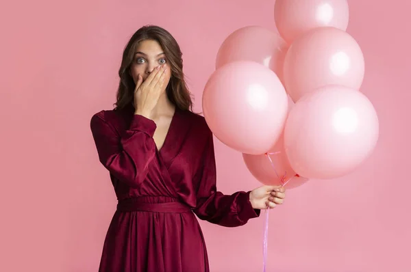 Chica sorprendida sosteniendo globos y cubriendo la boca con la mano en shock — Foto de Stock