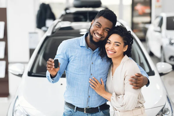 Africano casal americano mostrando carro chave em pé no automóvel Showroom — Fotografia de Stock