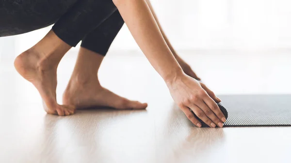 Woman rolling exercise yoga mat on wood floor at studio — Stock Photo, Image