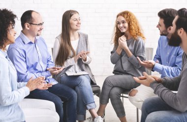 Rehabilitasyondaki terapi seansında insanlar genç bayanı alkışlıyor.