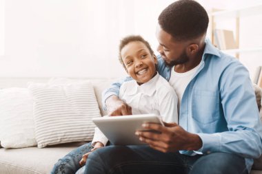 Afro baba ve kızı tabletten elbise ve oyuncak sipariş ediyorlar.