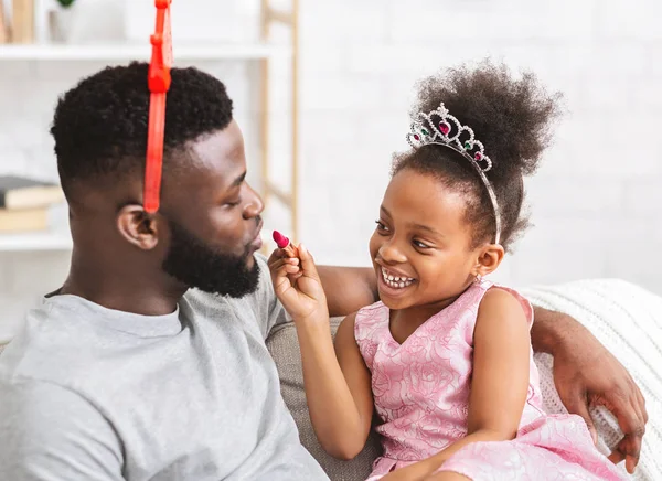 Sorrindo afro pequena filha segurando batom, brincando com o pai — Fotografia de Stock