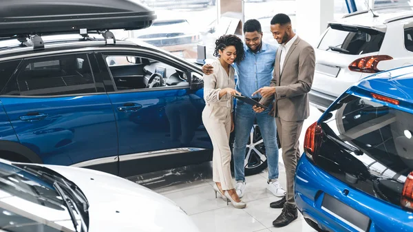 Casal visitando Car Dealership conversando com vendedor no Auto Showroom — Fotografia de Stock