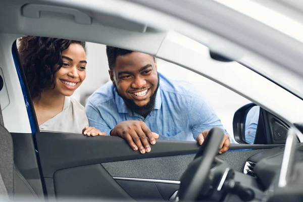 Afrikanische Eheleute betrachten Autoinnenraum und kaufen Fahrzeug im Geschäft — Stockfoto