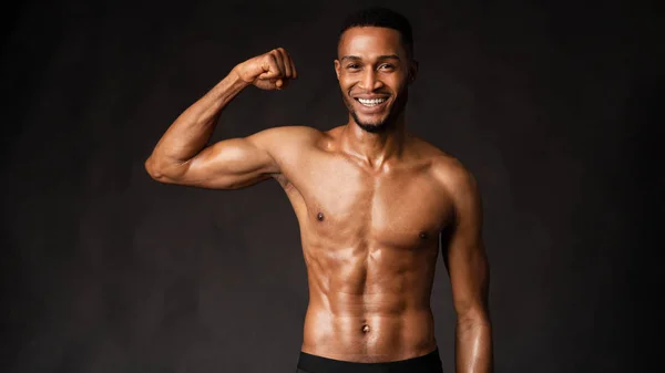 Sonriente hombre negro mostrando el cuerpo en la pared gris oscuro — Foto de Stock