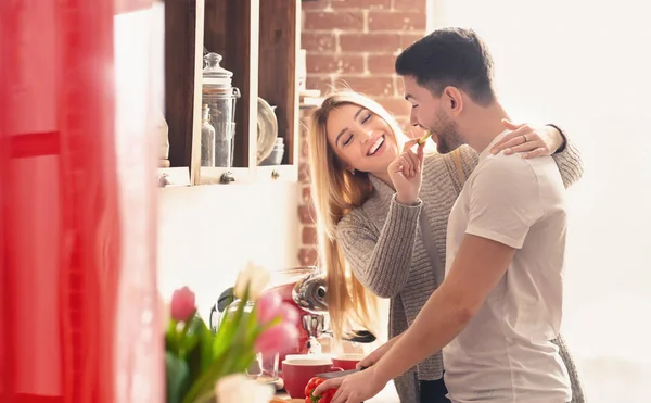 Woman feeding her boyfriend with piece of paprika before breakfast — Stock Photo, Image