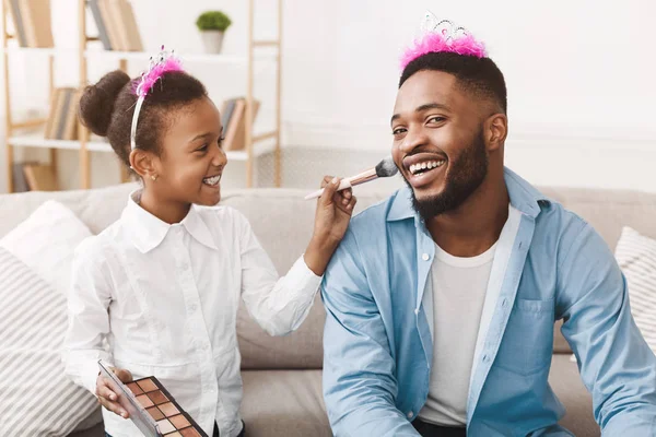 Brincar juntos. Pequena princesa colocando maquiagem em seu pai rainha — Fotografia de Stock