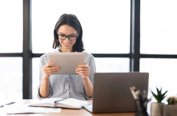 Chica joven sosteniendo la tableta y utilizando el ordenador portátil — Foto de Stock