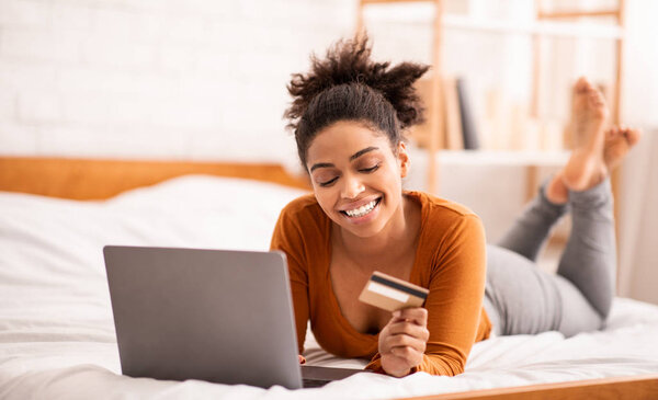 Девушка с помощью кредитной карты и ноутбука покупки в Интернете на дому
