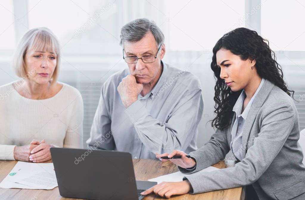 Unhappy mature couple talking to financial advisor at home