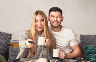 Neşeli milenyum çifti çay içip televizyon izliyor.