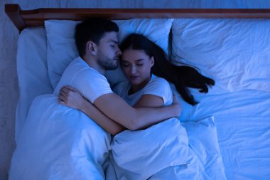 Sevgi dolu bir çift evde yatakta uyuyor, manzaranın üstünde.