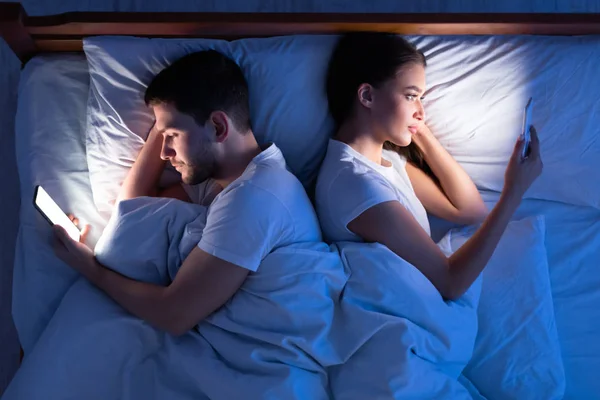 Inselat Sot Și Nevasta Texting Lying Back-To-Back În Dormitor, Top-View — Fotografie, imagine de stoc