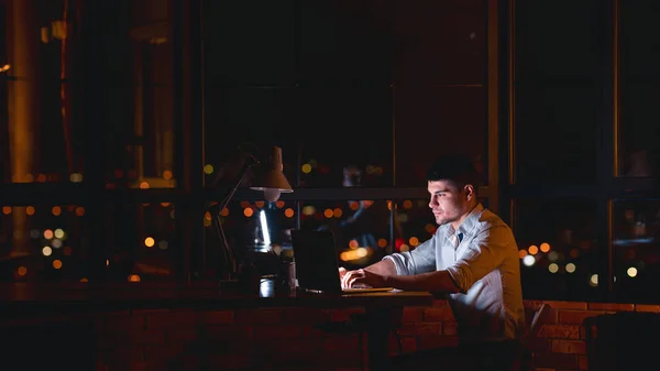 Man Working On Laptop Sitting In Office At Night, Panorama