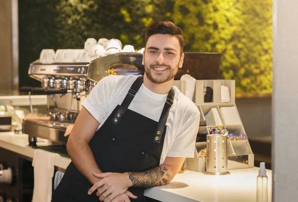 Barista Guy pozowanie w pobliżu ekspres do kawy stoi w kawiarni — Zdjęcie stockowe