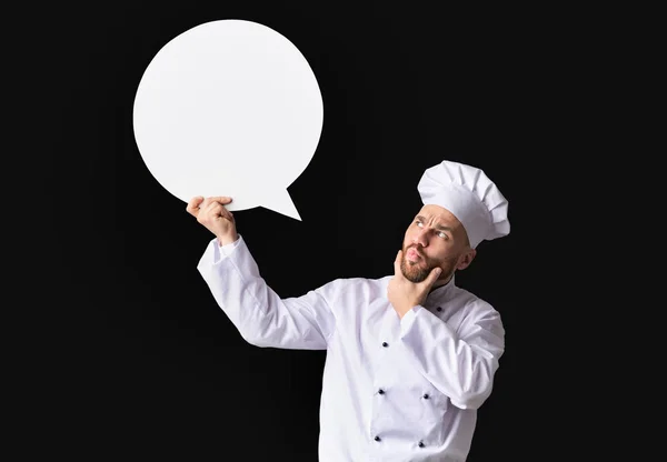 Zaskoczony szef kuchni gospodarstwa White Speech Bubble stoi na czarnym tle — Zdjęcie stockowe