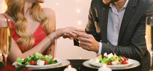 Oigenkännlig man sätter ring på flickvänner hand under middagen i restaurangen — Stockfoto