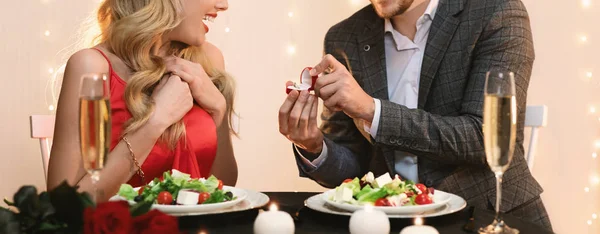 Mann macht seiner überraschten Freundin beim Abendessen im Restaurant einen Heiratsantrag — Stockfoto