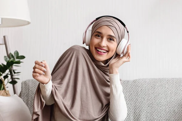 Gadis muslim modern mendengarkan musik di headphone nirkabel di rumah — Stok Foto