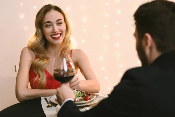 Casal feliz Clinking taças de vinho tinto no jantar romântico no restaurante — Fotografia de Stock
