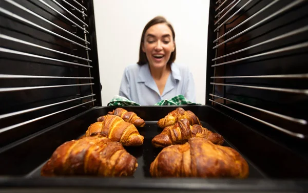 Femeia veselă care ia croissante crocante delicioase din cuptor — Fotografie, imagine de stoc