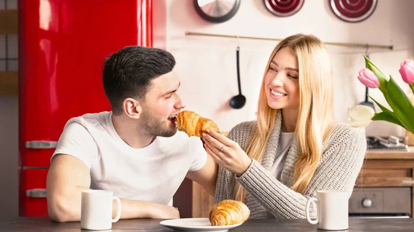 Joven alegre dando croissant a su novio — Foto de Stock