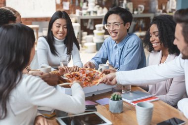 Young colleagues having fun while eating pizza at office