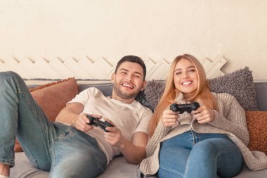 Happy couple holding joysticks and playing video game