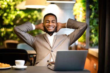 Satisfied black manager leaning back at the bar