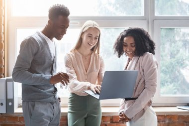 Cheerful girl showing her excited colleagues laptop screen