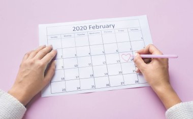 Female hands passing round with heart in Calendar on 14 Februar