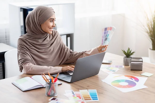 Moslim vrouwelijke ontwerper werkt met kleurenpalet en laptop op kantoor — Stockfoto