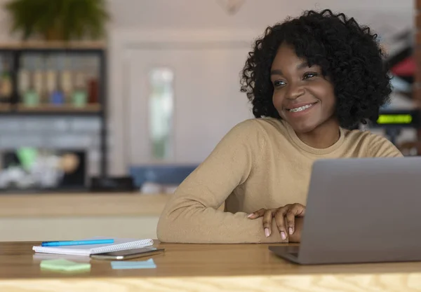 Una donna sorridente seduta al bar. lavorando online dal computer portatile — Foto Stock