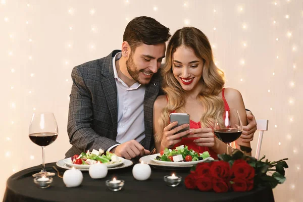 Young Couple Using Smartphone Together During Romantic Dinner In Restaurant — Stok fotoğraf