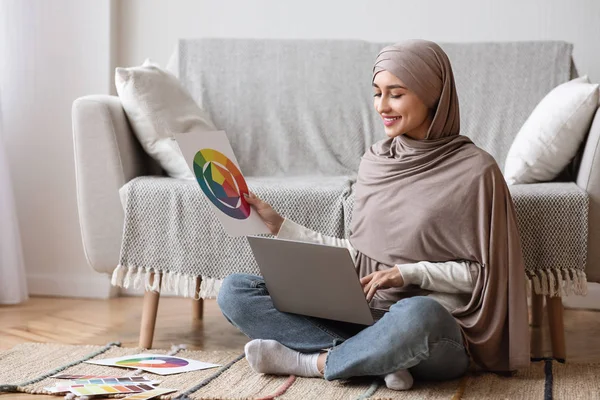 Diseñadora árabe sentada con laptop y muestras de color en el piso — Foto de Stock