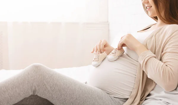Wanita hamil bermain dengan booties kecil dan perutnya — Stok Foto
